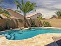 Relaxing backyard oasis showcasing a refreshing pool, mature palm trees, and a charming waterfall feature at 45726 W Long Way, Maricopa, AZ 85139
