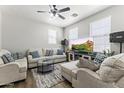 Bright living room with neutral sofas, a ceiling fan, a modern rug, and a large flat-screen TV at 5421 W Burton Dr, Phoenix, AZ 85043