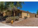 Side view of the tan home, showcasing desert landscaping and the fenced backyard at 23682 W Bowker St, Buckeye, AZ 85326