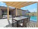 Inviting outdoor patio with a pergola, dining set, and comfortable seating overlooking the pool area at 25876 N 162Nd Dr, Surprise, AZ 85387