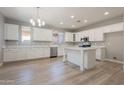 Bright kitchen featuring white cabinets, an island, modern appliances, and wood floors at 408 W Sweet Shrub Ave, San Tan Valley, AZ 85140