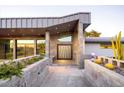 Inviting front entry with a unique door design, complemented by elegant landscaping and concrete accents at 6529 N Mountain View Dr, Paradise Valley, AZ 85253