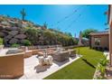 Relaxing backyard with built-in seating, fire pit, artificial grass, and mountain views at 11070 E Bent Tree Dr, Scottsdale, AZ 85262