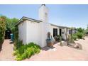 White single story home with unique chimney, tile roof, desert landscaping, and brick driveway at 1441 E Hubbell St, Phoenix, AZ 85006
