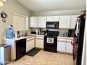 Efficient kitchen features white cabinets, black appliances, and tile flooring at 15706 W Young St, Surprise, AZ 85374