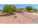 Well-maintained front yard featuring mature trees, desert landscaping, and a terracotta-tiled roof home at 15980 W Quail Creek Ln, Surprise, AZ 85374