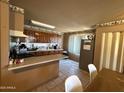 Well-equipped kitchen with tile flooring, generous counter space, and wooden cabinets, perfect for culinary endeavors at 3937 W Stella Ln, Phoenix, AZ 85019