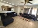 Inviting living room featuring tile flooring, a comfortable sectional sofa, and a ceiling fan for added comfort at 3937 W Stella Ln, Phoenix, AZ 85019