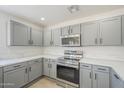 Updated kitchen with gray cabinets, stainless steel appliances, white quartz countertops, and hardwood flooring at 12813 W Paradise Dr, El Mirage, AZ 85335