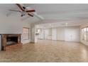 Open living room with fireplace, ceiling fan, neutral tile flooring, and an open view to the kitchen at 3433 E Betty Elyse Ln, Phoenix, AZ 85032