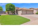 Charming single-story home featuring a tile roof, lush lawn, mature tree, and a two-car garage at 8354 W Marlette Ave, Glendale, AZ 85305