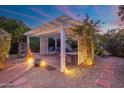 Covered patio at dusk is illuminated by landscape lighting and features a seating area and fire pit at 3550 E Edna Ave, Phoenix, AZ 85032