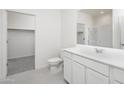 Bright bathroom with sleek white cabinetry, modern fixtures, and a glass-enclosed shower near a spacious closet at 10318 S 58Th Ln, Laveen, AZ 85339