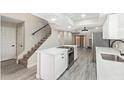 Open kitchen with stainless steel appliances, white cabinetry, and modern island adjacent to staircase and living room at 2107 W Lane Ave, Phoenix, AZ 85021
