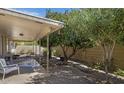 Lush backyard featuring a covered patio, mature trees, and low-maintenance gravel landscaping at 4117 E Carol Ave, Mesa, AZ 85206