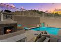 Beautiful pool and fireplace area with lush landscaping, and a water feature provides a tranquil setting at 6106 W Spur Dr, Phoenix, AZ 85083