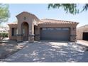 Inviting front exterior featuring a tile roof, a two-car garage, and an arched entryway at 1381 E Prickly Pear Dr, Casa Grande, AZ 85122