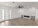 Bright, open-concept living room with wood floors, modern fireplace, and stylish ceiling fan at 15582 W Jomax Rd, Surprise, AZ 85387