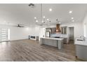 Open-concept living space with modern lighting, fireplace, wood floors, and kitchen at 15582 W Jomax Rd, Surprise, AZ 85387