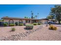 Well-maintained single-story home with desert landscaping, rock features, and mature palm trees in the yard at 2446 E Hale St, Mesa, AZ 85213
