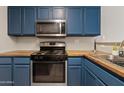 Kitchen showcasing blue cabinets, stainless steel appliances, and butcher block countertops at 125 S 56Th St # 27, Mesa, AZ 85206