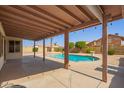 Covered patio overlooking a backyard with a swimming pool, mature trees, and desert landscaping at 7709 W Hearn Rd, Peoria, AZ 85381