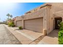 Exterior view of tan townhomes, featuring two-car garages, sidewalks, and desert landscaping at 8540 N Central Ave # 6, Phoenix, AZ 85020
