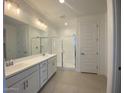 Modern bathroom featuring dual sinks, sleek cabinets, a glass-enclosed shower, and tile flooring at 10217 W Fairmount Ave, Avondale, AZ 85392