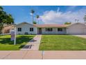 A well-manicured front yard leads to a charming single-story home with a welcoming walkway and a clean facade at 1917 E Jensen St, Mesa, AZ 85203