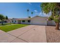 Spacious home featuring a long driveway leading to a two-car garage, set against a backdrop of palm trees at 1917 E Jensen St, Mesa, AZ 85203