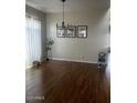 This bright living room features wood floors and a modern chandelier at 41763 W Mano Pl, Maricopa, AZ 85138