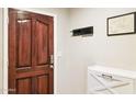 View of the home entryway with white storage cabinet, dark trim door and coat rack at 7756 N 19Th Ln, Phoenix, AZ 85021