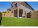 Fenced backyard with synthetic grass, covered patio, and neutral-toned stucco house at 2725 E Mine Creek Rd # 1149, Phoenix, AZ 85024