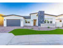 Modern home featuring a stone facade, neutral paint, manicured lawn, and a gray garage door at 7583 W Gelding Dr, Peoria, AZ 85381