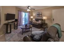 A cozy living room features leather sofas, a ceiling fan, and a sliding glass door to the outside at 2228 N 52Nd St # 227, Phoenix, AZ 85008