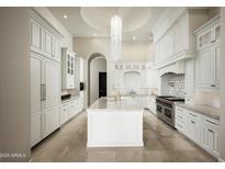 Bright kitchen features an island, white cabinetry, stone countertops and stainless appliances at 6112 E Quartz Mountain Rd, Paradise Valley, AZ 85253