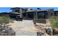 A contemporary home featuring a stone-paved driveway lined with desert landscaping and modern architectural details at 37445 N 104Th Pl, Scottsdale, AZ 85262