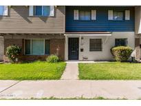 Charming townhome showcasing a well-maintained front yard with a walkway to the black-colored front door at 1673 W Hazelwood St, Phoenix, AZ 85015
