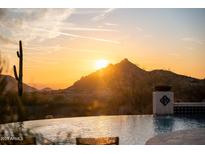 Backyard features a beautiful pool overlooking a desert landscape and a stunning orange sunset at 24724 N 119Th Pl, Scottsdale, AZ 85255