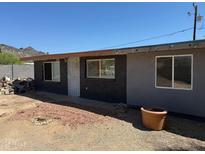 Side exterior of a grey house with a dirt and gravel yard with mountain views in the background at 1535 E Christy Dr, Phoenix, AZ 85020