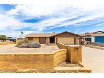 Tan home featuring an attached garage and mature landscaping out front with a decorative wall at 5625 N 47Th Ave, Glendale, AZ 85301