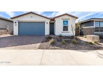 Charming single-story home featuring a brick driveway, blue garage door, and a nicely landscaped front yard at 40075 W Elm Dr, Maricopa, AZ 85138