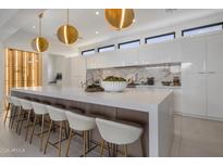 Modern kitchen with white cabinets, marble backsplash, and large island at 24863 N 103Rd N Way, Scottsdale, AZ 85255