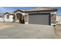 White single story home with gray garage door and stone accents at 12827 S Hermit Rd, Buckeye, AZ 85326