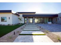 Contemporary home with stone accents and manicured landscaping leading to a glass front door at 12232 N 65Th Pl, Scottsdale, AZ 85254