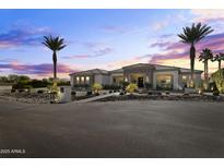 Stunning desert home with stone accents and palm trees at sunset at 18223 W Rancho Ct, Litchfield Park, AZ 85340