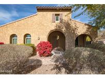 Tan stucco house with arched entryway, red flowers, and mature shrubs at 18206 W Sells Dr, Goodyear, AZ 85395