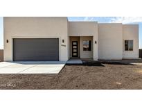 Modern home with a gray garage door, light-colored stucco exterior and black trimmed windows at 22205 W Ocupado Dr, Wittmann, AZ 85361