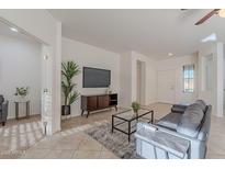 Bright living room features tiled floors, comfy couch, and a large TV at 19661 N Echo Rim Dr, Surprise, AZ 85387