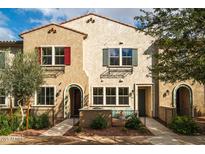 Tan two-story townhome with red and green shutters, arched entryways, and a small patio at 1917 E Hampton Ln # 109, Gilbert, AZ 85295